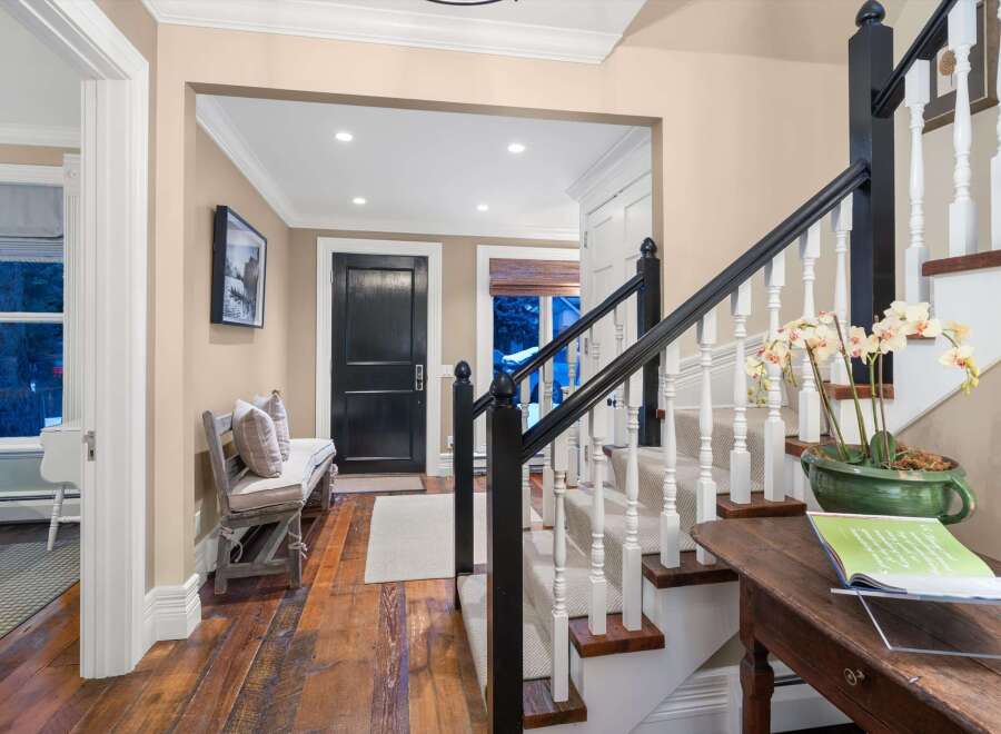 Step into luxury with this stunning entryway, showcasing a beautiful staircase with white balusters and a dark wood handrail.