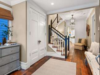 Step into this inviting entryway, showcasing a beautiful staircase and hardwood floors.
