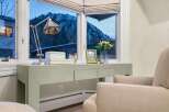 This stunning property boasts a serene interior with a desk area perfectly positioned by a window, offering breathtaking views of a snow-covered mountain.