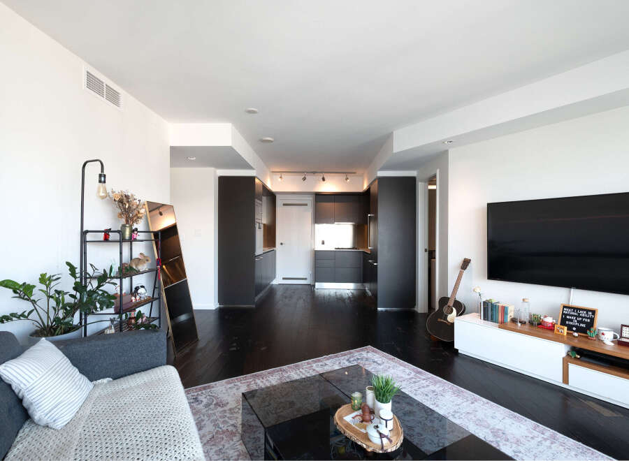 This stunning modern apartment boasts an open-concept living space with dark hardwood floors and sleek, contemporary design.