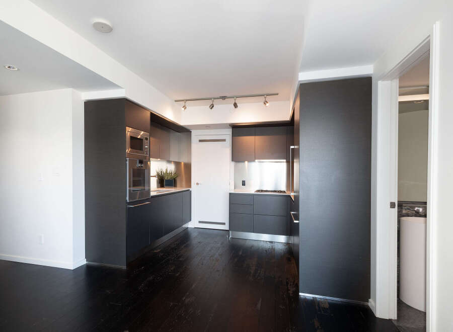 Experience modern luxury in this stunning kitchen! Featuring sleek, dark cabinetry, stainless steel appliances, and a beautiful hardwood floor, this space is perfect for both cooking and entertaining.