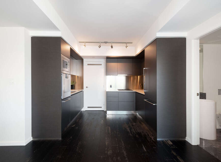 This modern kitchen boasts sleek, dark cabinetry and stainless steel accents, creating a sophisticated and contemporary atmosphere.