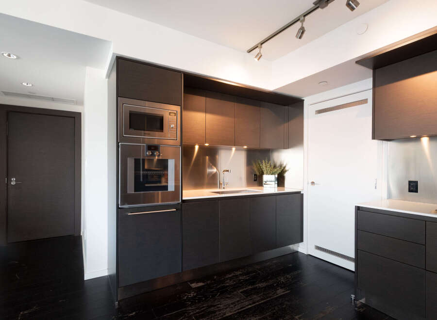 This modern kitchen boasts sleek, dark cabinetry and stainless steel appliances, creating a sophisticated and functional space.