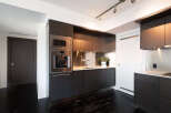 This modern kitchen boasts sleek, dark cabinetry and stainless steel appliances, creating a sophisticated and functional space.