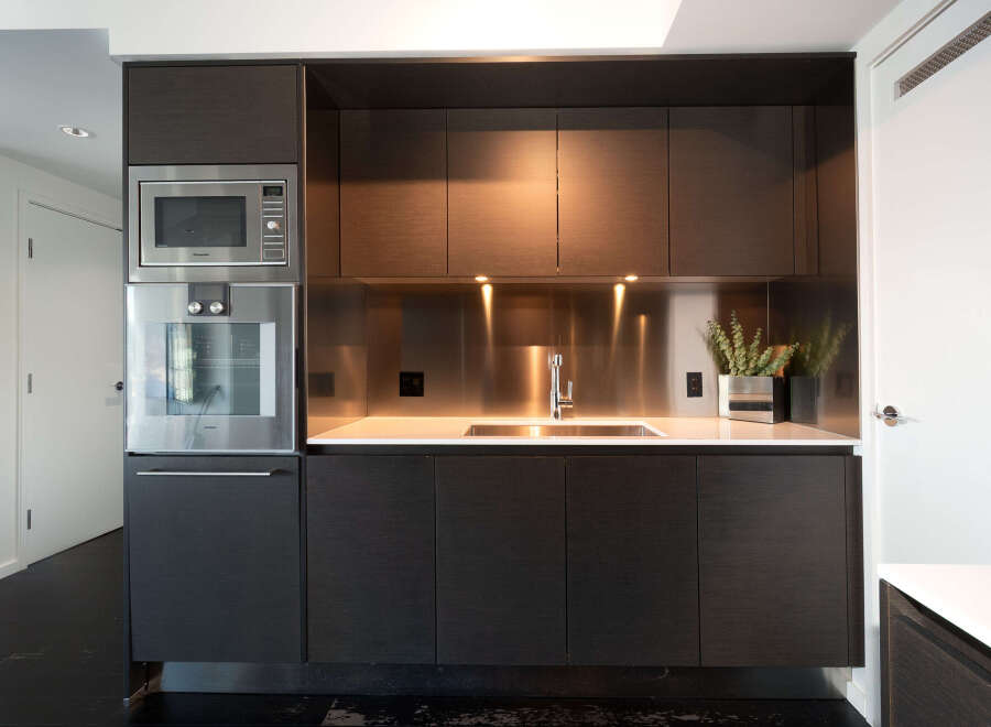 This modern kitchen boasts sleek, dark wood cabinetry and stainless steel appliances, creating a sophisticated and functional space.
