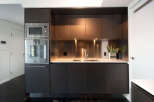 This modern kitchen boasts sleek, dark wood cabinetry and stainless steel appliances, creating a sophisticated and functional space.