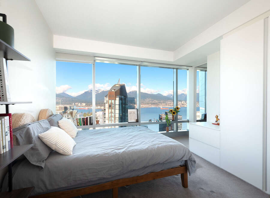 Experience luxury living in this stunning bedroom with breathtaking city and mountain views.