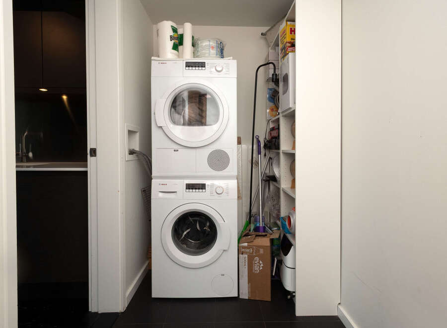 Discover the convenience of this modern laundry space, featuring a stacked washer and dryer for efficient use of space.