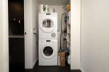 Discover the convenience of this modern laundry space, featuring a stacked washer and dryer for efficient use of space.