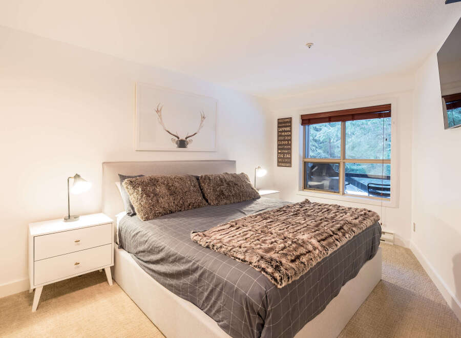 This cozy bedroom features a comfortable king-sized bed with plush bedding and a stylish faux fur throw.