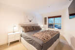 This cozy bedroom features a comfortable king-sized bed with plush bedding and a stylish faux fur throw.