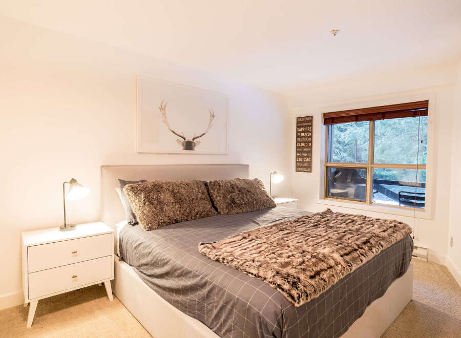 This cozy bedroom features a comfortable bed with plush pillows and a stylish faux fur throw.