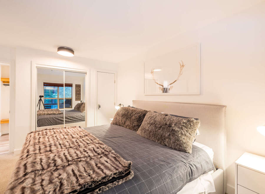 This cozy bedroom features a plush bed with a faux fur throw and pillows, creating a warm and inviting atmosphere.