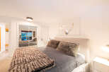 This cozy bedroom features a plush bed with a faux fur throw and pillows, creating a warm and inviting atmosphere.