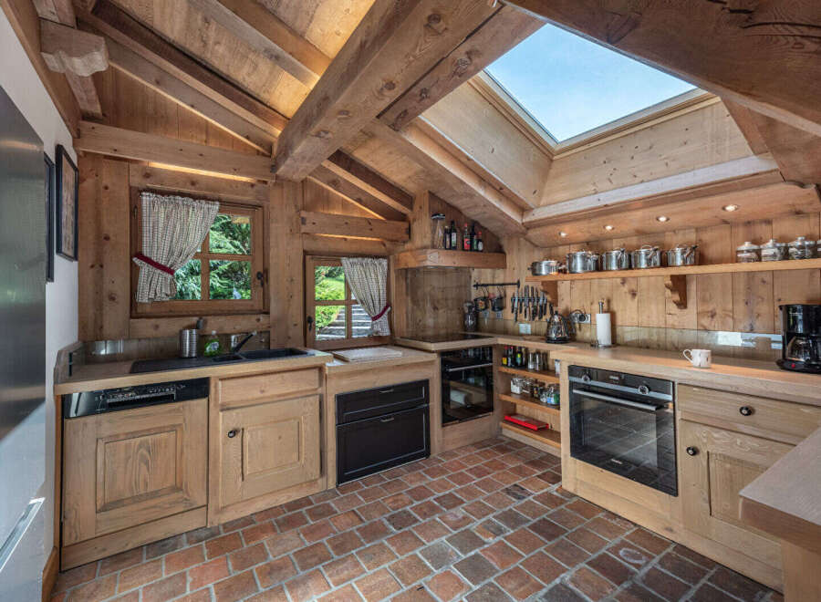 Step into rustic elegance with this stunning kitchen, featuring exposed wooden beams and a charming brick floor.