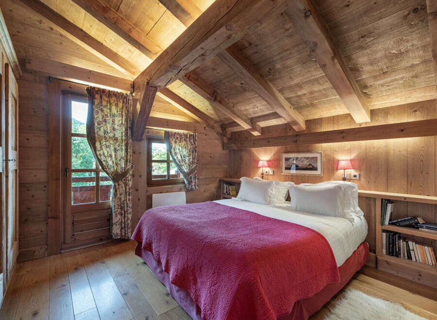 Experience the warmth and charm of this cozy bedroom, featuring stunning wooden beams and paneling that create a rustic ambiance.