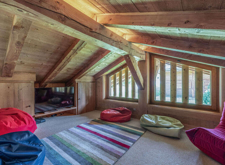 This cozy attic space features a rustic wooden interior with exposed beams and natural light streaming through the windows.