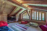 This cozy attic space features a rustic wooden interior with exposed beams and natural light streaming through the windows.
