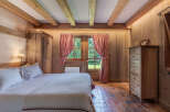 This charming bedroom exudes rustic elegance with its wooden walls, ceiling beams, and terracotta tile flooring.