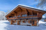 This stunning wooden chalet, nestled in a snowy landscape, offers a cozy retreat.