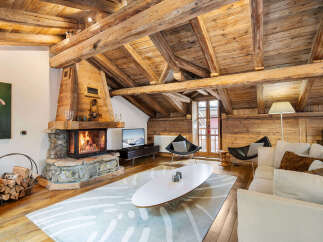 Experience rustic luxury in this stunning living room, featuring a magnificent stone fireplace and exposed wooden beams that create a warm, inviting ambiance.