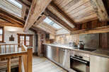 Experience rustic charm in this mountain kitchen, featuring exposed wooden beams and a sloped ceiling with skylights that flood the space with natural light.