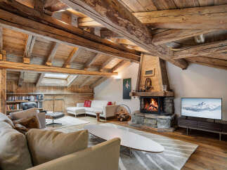 Experience rustic charm and modern comfort in this stunning living room, featuring exposed wooden beams and a grand stone fireplace.