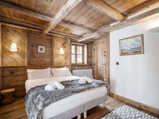 Experience rustic charm in this cozy bedroom featuring exposed wooden beams and walls, creating a warm and inviting atmosphere.