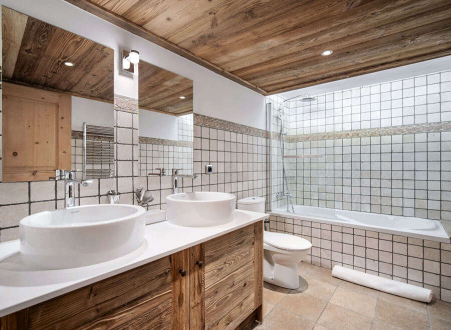 Experience rustic charm in this mountain-inspired bathroom, featuring a double vanity with vessel sinks and wooden cabinetry.
