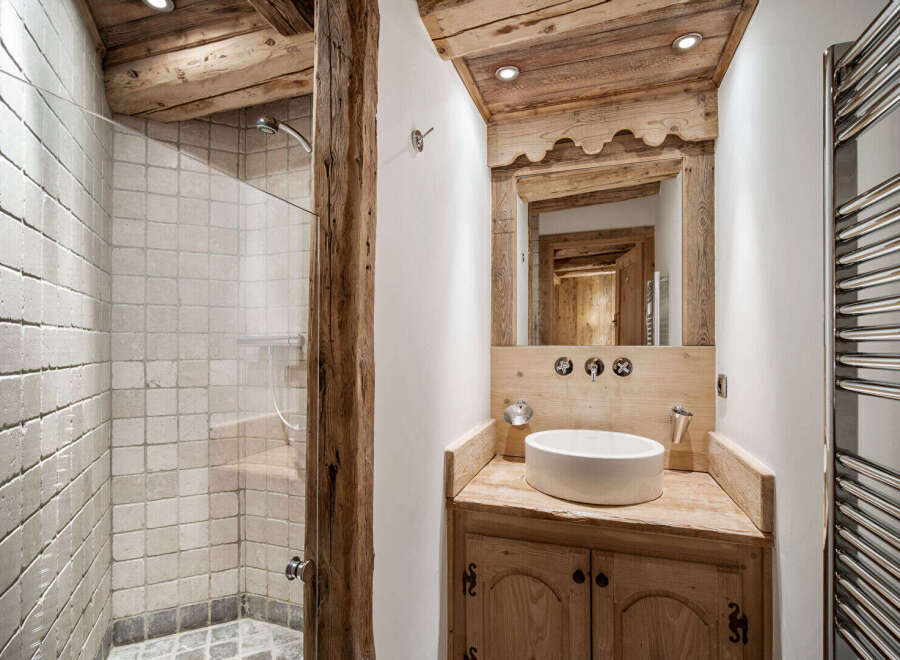 Experience rustic charm in this mountain bathroom, featuring a spacious walk-in shower with textured tile and a wooden beam accent.