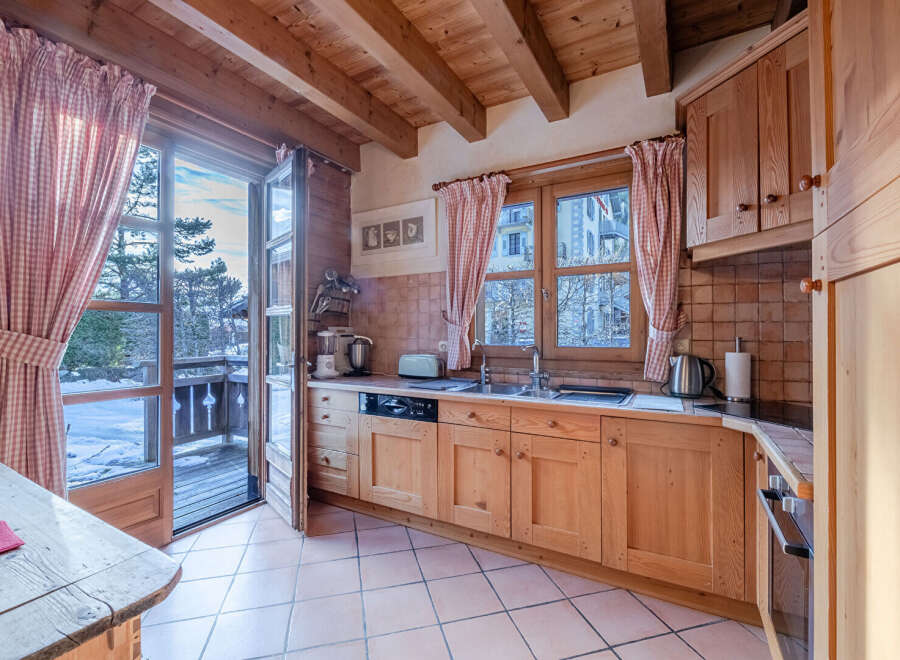 This charming kitchen boasts a warm, inviting atmosphere with its wooden cabinetry and exposed beams.