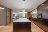 This modern kitchen boasts a sleek design with dark cabinetry and a contrasting white countertop island.