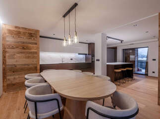Experience modern elegance in this stunning property, featuring a spacious dining area with a large wooden table and stylish chairs.