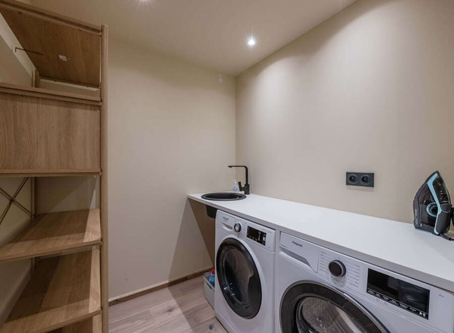 This modern laundry room boasts a sleek design with a washing machine and a sink, perfect for efficient home management.