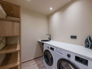 This modern laundry room boasts a sleek design with a washing machine and a sink, perfect for efficient home management.