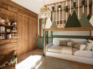 This charming bedroom features a unique bunk bed design with a cozy seating area below, perfect for relaxation.