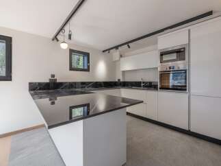 This modern kitchen boasts sleek, white cabinetry and a stunning black marble countertop, creating a sophisticated and stylish space.