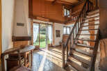 Step into this charming home featuring a cozy fireplace and a rustic wooden staircase.