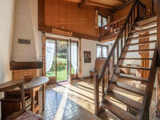 Step into this charming home featuring a cozy fireplace and a rustic wooden staircase.