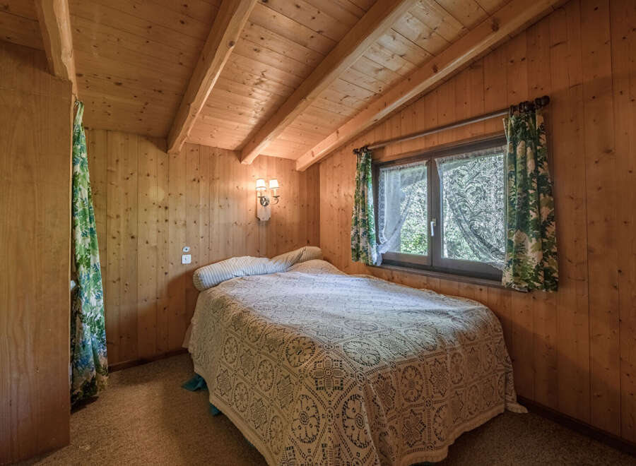 This cozy bedroom features warm wood paneling and a charming ambiance.