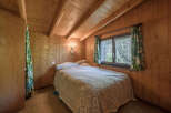 This cozy bedroom features warm wood paneling and a charming ambiance.