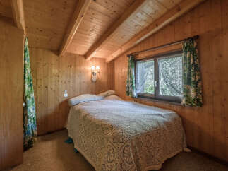 This cozy bedroom features warm wood paneling and a charming ambiance.