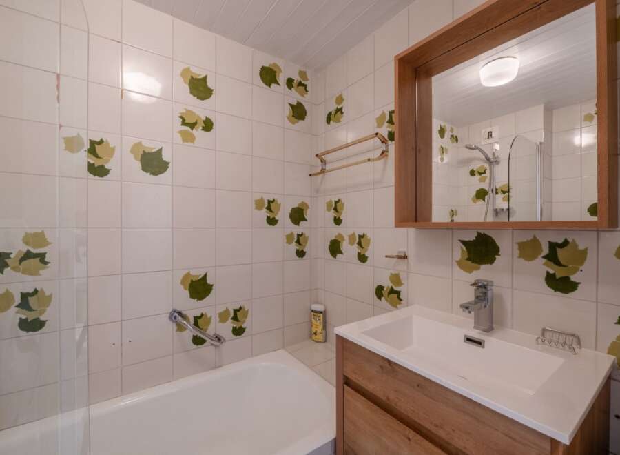 This charming bathroom features a unique design with leaf-patterned tiles, creating a fresh and inviting atmosphere.