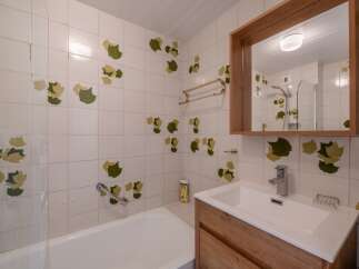 This charming bathroom features a unique design with leaf-patterned tiles, creating a fresh and inviting atmosphere.