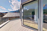 Experience breathtaking views from this modern property featuring a spacious balcony with a sleek glass railing.