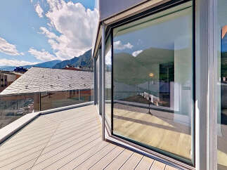 Experience breathtaking views from this modern property featuring a spacious balcony with a sleek glass railing.
