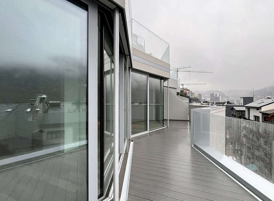 Experience breathtaking views from this modern property featuring expansive glass windows and a spacious balcony.