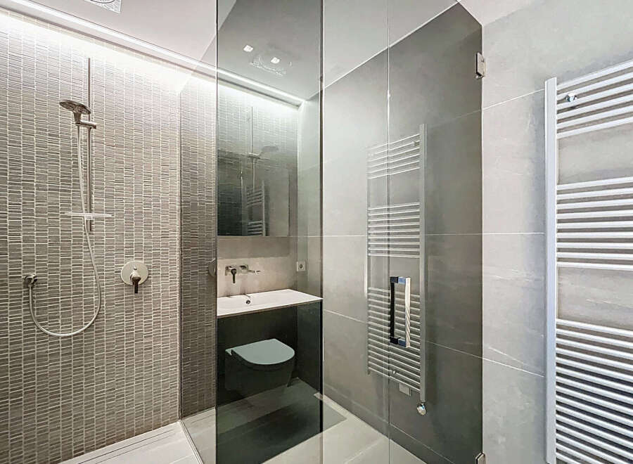 Step into a modern bathroom oasis! This stunning space features a sleek glass shower enclosure, a stylish heated towel rack, and elegant tile work.