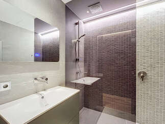 Step into a modern bathroom oasis! This stunning space features sleek gray tiles, a contemporary sink, and a luxurious shower area.