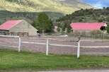 Discover the charm of this equestrian estate, featuring a spacious riding arena and multiple barns with vibrant red roofs.
